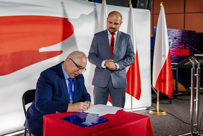 Na zdjęciu przy stole stoi dyrektor IPN Wrocław, przy stole podpisuje umowę Franciszek Kopeć.