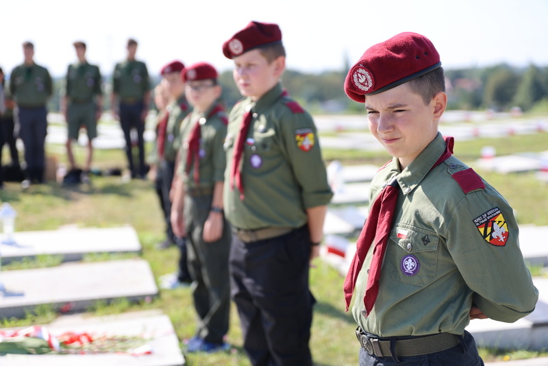 Na pierwszym planie harcerz stojący nad grobem bohatera