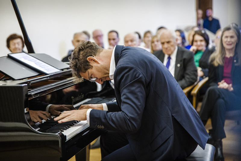 Zdjęcie prezentuje moment koncertu, siedzący muzyk przy fortepianie