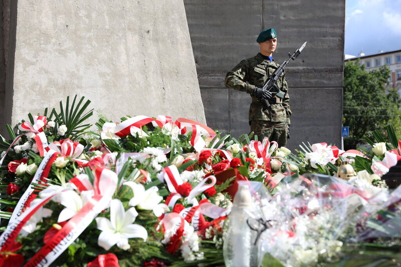Zdjęcie prezentuje pomnik wraz z wiązankami kwiatów