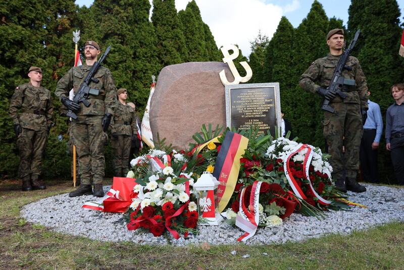 zdjęcie pomnika z wiązankami kwiatów z wartą honorową po bokach