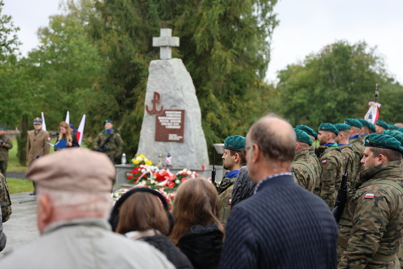 na pierwszym planie widać ludzi, w tle pomnik