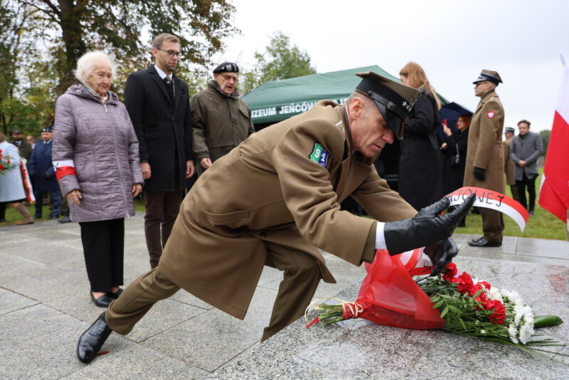 zdjęcie przedstawia moment składania kwiatów pod pomnikiem