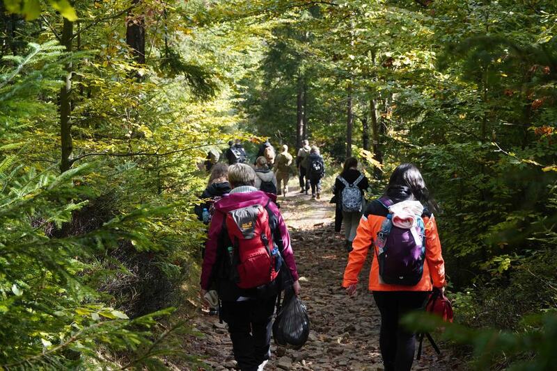 Zdjęcie przedstawia grupę osób maszerujących w lesie