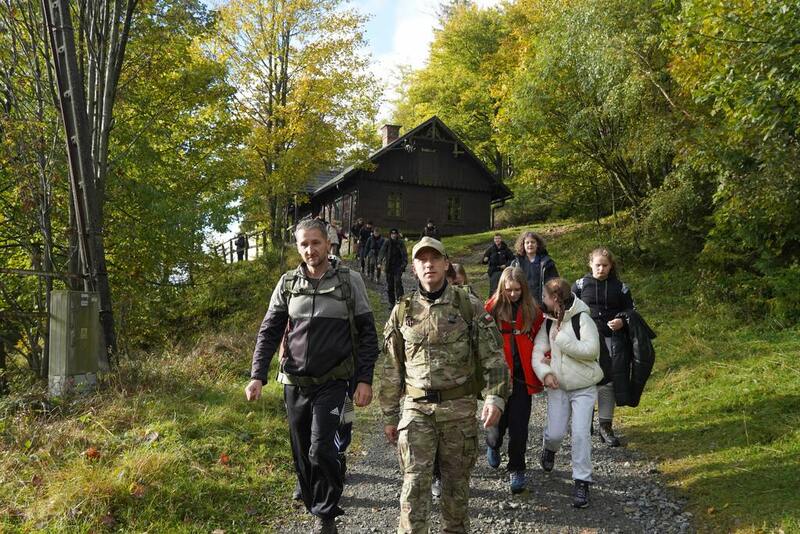 Zdjęcie przedstawia grupę osób maszerujących w lesie
