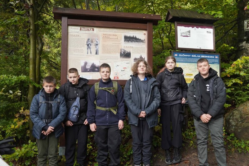 Zdjęcie przedstawia grupę osób przed tablicą informacyjną/ zdjęcie grupowe