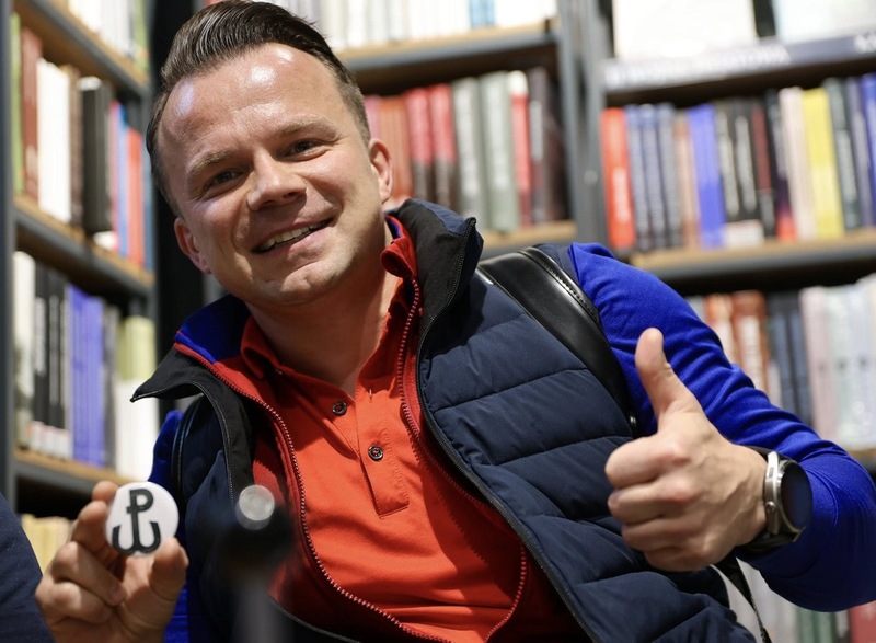 Mężczyzna zadowolony pokazujący znaczek, który dostał w księgarni