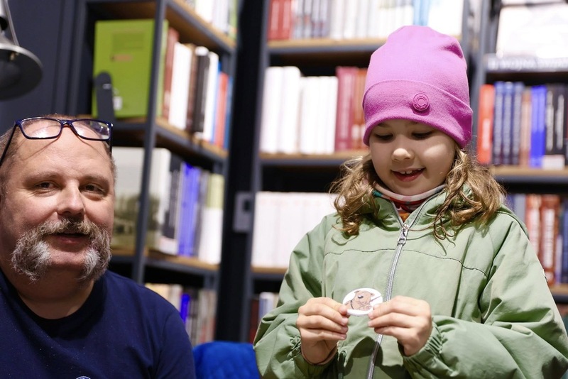 Dziewczynka zadowolona pokazująca znaczek, który dostała w księgarni