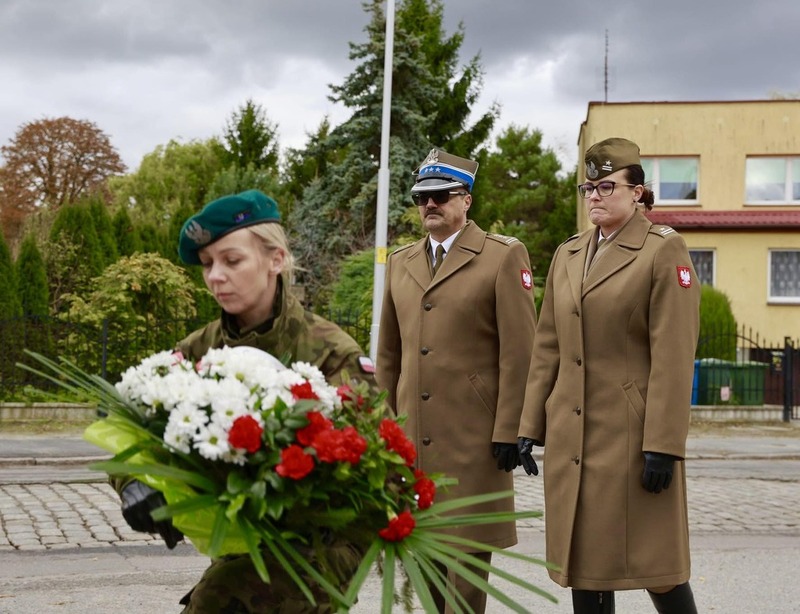 na zdjęciu moment składania kwiatów, na pierwszym planie żołnierz trzymający wiążankę