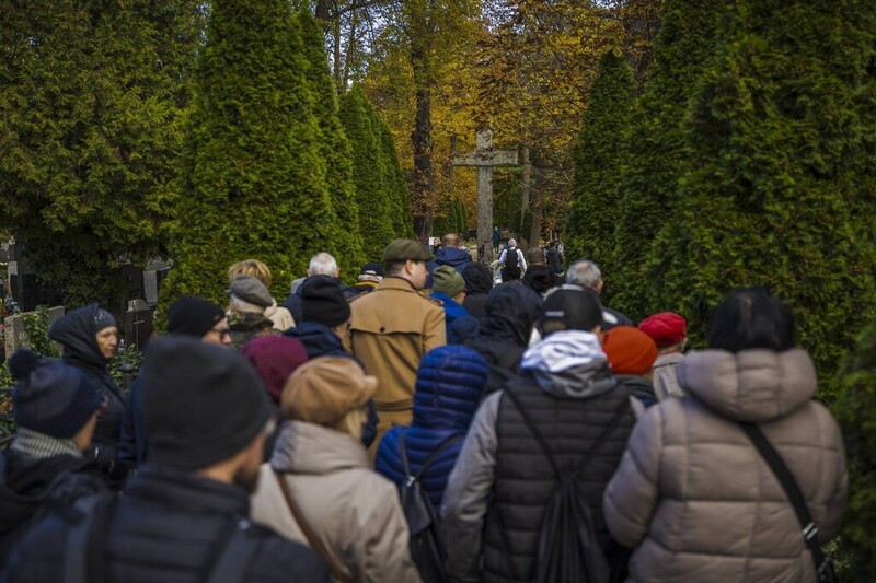 na zdjęciu od tyłu grupa osób w trakcie zwiedzania między nagrobkami