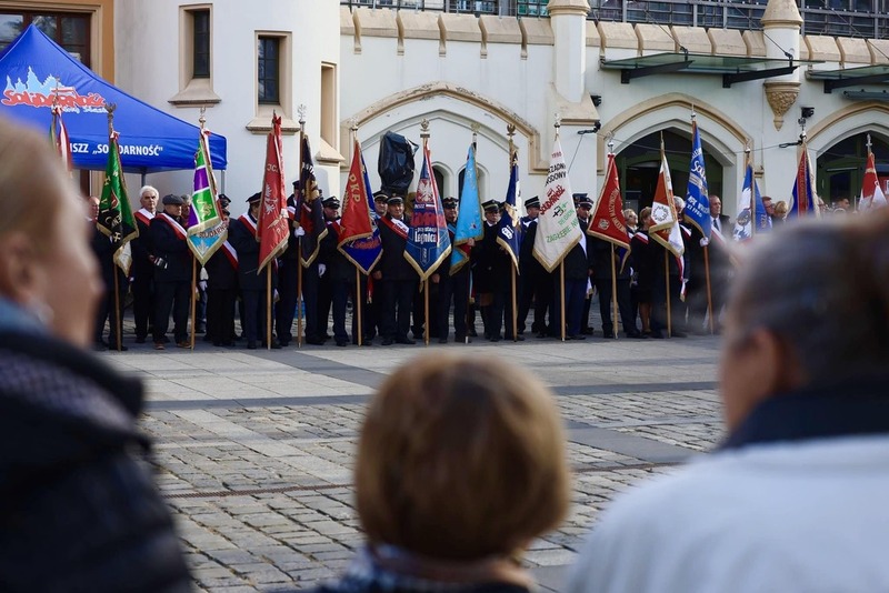 zdjęcie przedstawia w tle stojące w rzędzie poczty sztandarowe