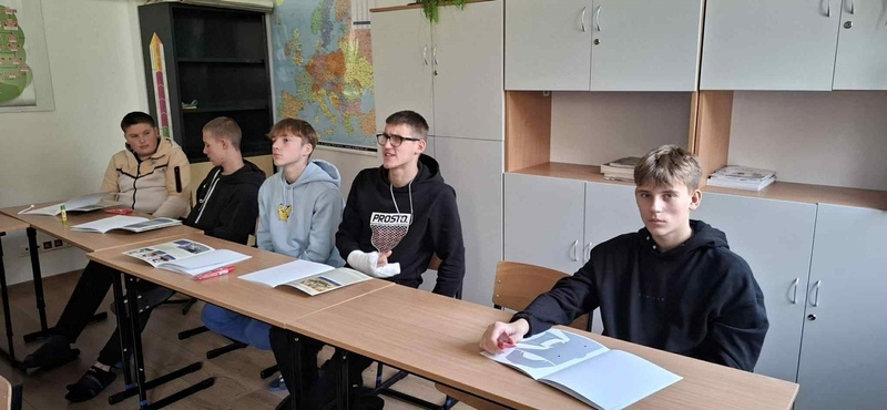 przy stole siedzi młodzież i słucha wykładu