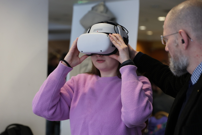 fragment pokazu możliwości VR IPN, dziewczyna zakłada okulary VR i odbiera instrukcję od pracownika IPN.