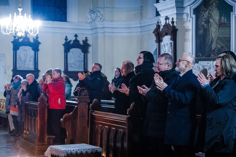 zdjęcie pokazuje koniec koncertu i ludzi klaskających stojąc w ławkach