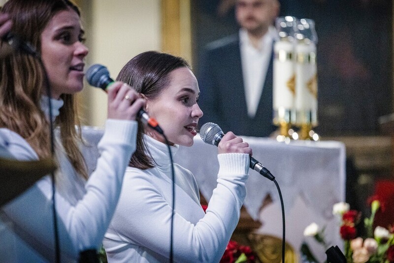 zdjęcie pokazuje fragment koncertu, przy ołtarzu stoją śpiewające ubrane w białe szaty kobiety