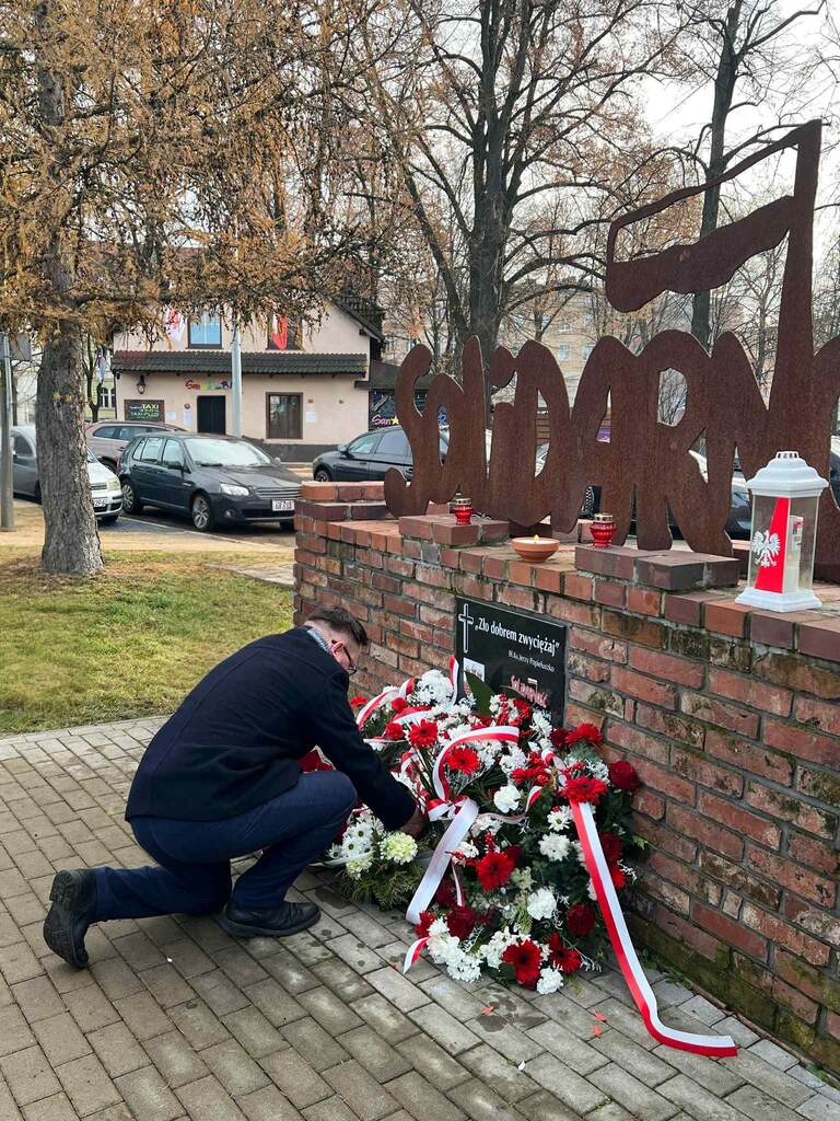 Zdjęcie pokazuje moment składania kwiatów pod pomnikiem Solidarności przez Grzefgorza Kowala