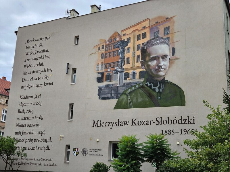 na zdjęciu rzut na ścianę, gdzie widnieje mural ze słowami pieśni Rozkwitały pąki białych róż