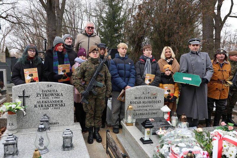 pamiątkowe zdjęcie uczestników wydarzenia, którzy stoją przy grobie Kozara