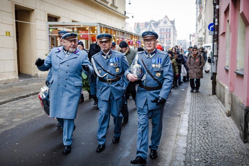 zdjęcie moment przemarszu, na pierwszym planie trzech mężczyznz w mundurach piusudczyków