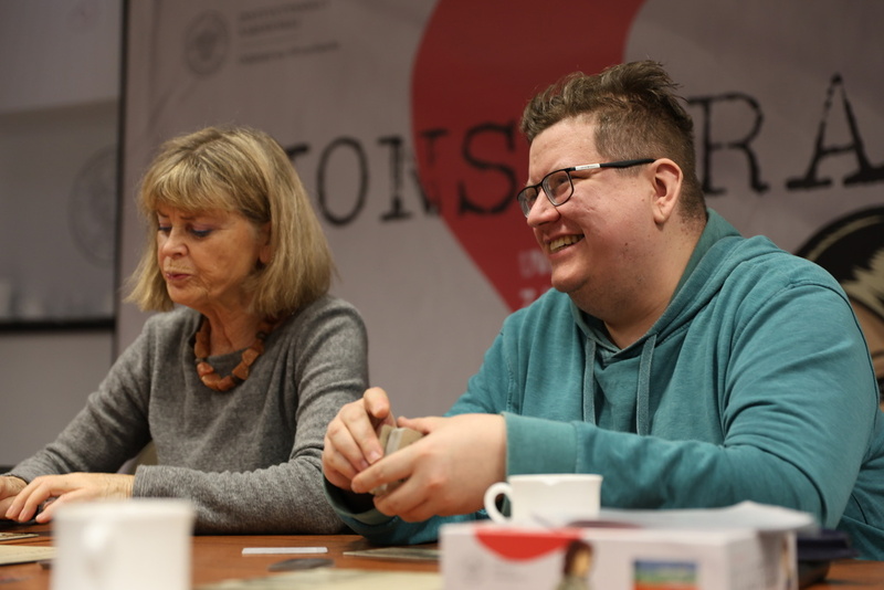 siedzący ludzie przy stole grający w grę