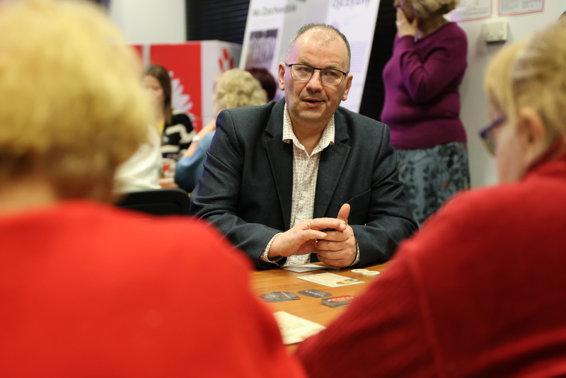 siedzący ludzie przy stole grający w grę