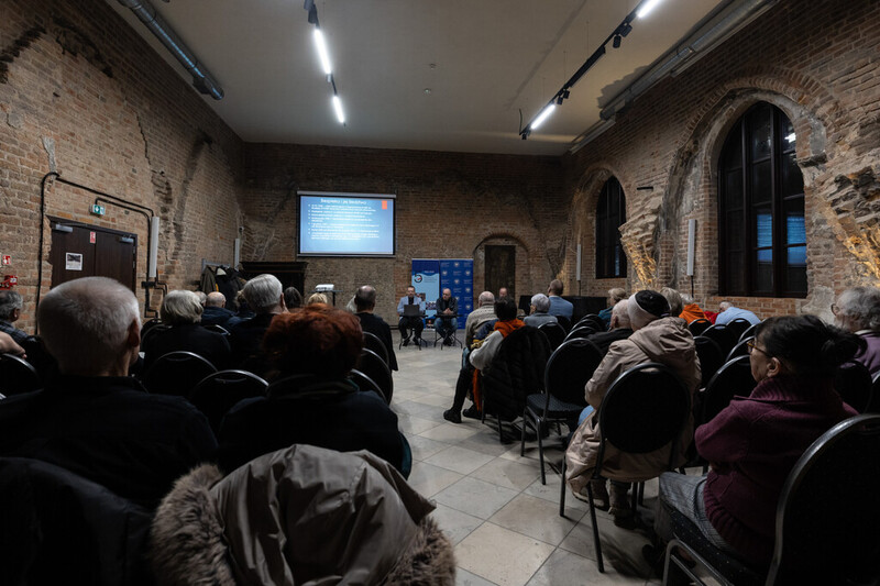zdjęcie prezentuje widok na widownię wydarzenia, siedzących ludzi na krzesłach