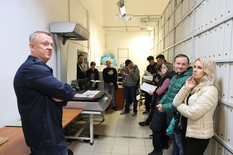 na pierwszym planie pracownik Archiwum mówiący o swojej pracy. W tle uczestnicy wydarzenia