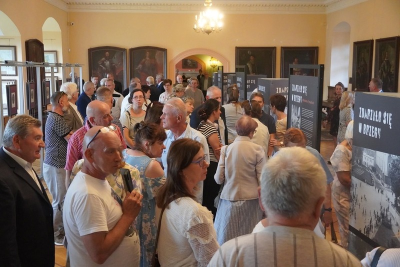 przy planszach stoją ludzie oglądają wystawę