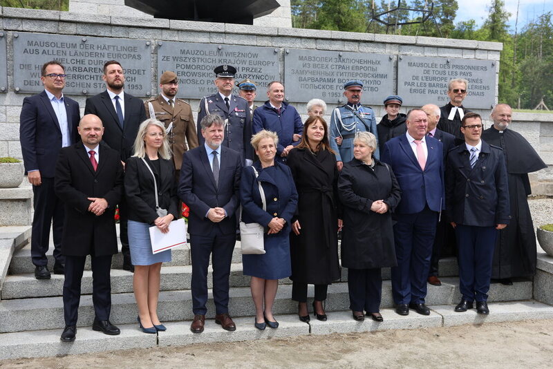 grupowe zdjęcie uczestników wydarzenia stojący pod pomnikiem