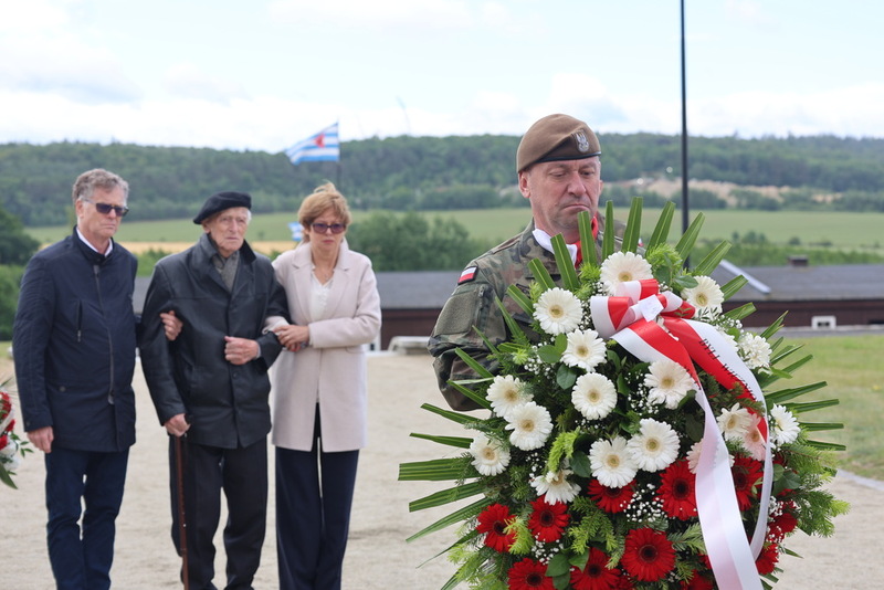 moment składania kwiatów, do pomnika podchodzi świadek historii, były więzień obozu