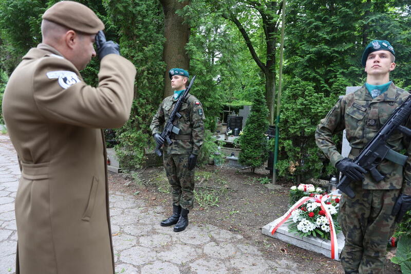 przed grobem stoi wyższy stopniem żołnierz i salutuje